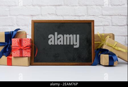 empty wood frame and stack of various gift boxes on white brick background Stock Photo