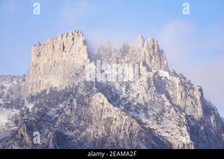 rocky peaks of the top of Mount Ai-Petri against the background of the sky in bright sunlight through a cloudy haze Stock Photo