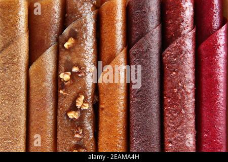 The pastille in the assortment is rolled up in the form of a tube. Various types of dried fruits and berry juices.Full frame. Natural product without sugar. Stock Photo