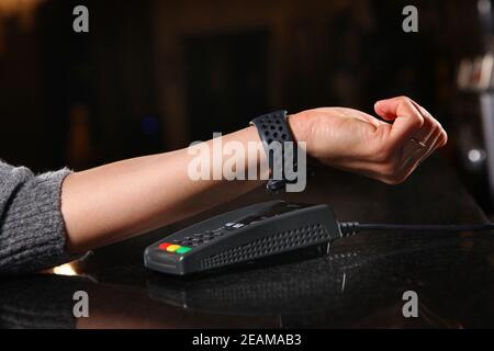 Payment for purchase hours through the terminal in the restaurant, shop. Women's hand close-up with a watch when paying for the purchase. Stock Photo