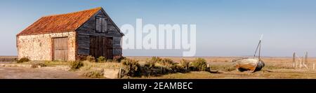 UK, Norfolk, Thornham, Old Harbour, 2109, April, 22: Coal Barn and old boat at Thornham, panoramic Stock Photo