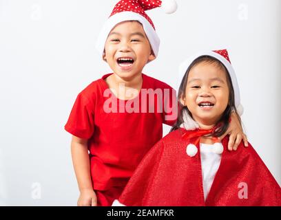 Kids dressed in red Santa Claus hat hugging together Stock Photo