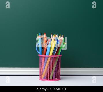 pink stationery glass with multi-colored wooden pencils and pens Stock Photo
