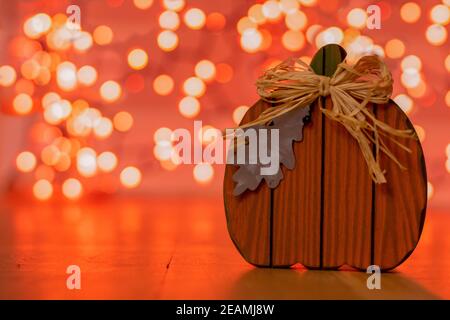 A Wood Pumpkin With a Metal Leaf With Orange Bokeh Behind It Stock Photo