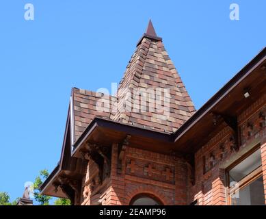 Part of the brick building of red brick and shingles on the roof Stock Photo