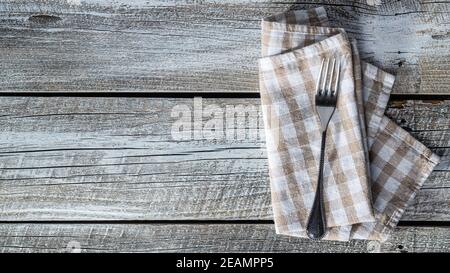 Fork and checkered napkin on wooden table. Stock Photo