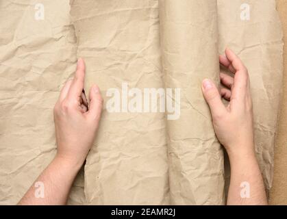 two female hands hold rolled brown paper Stock Photo