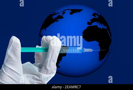 hand holds a syringe with the inscription vaccine symbolically in front of globe Stock Photo