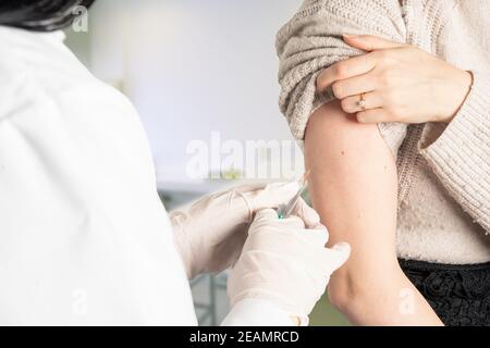 doctor vaccinates a patient with a syringe on her arm Stock Photo