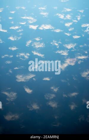 Blue sky and puffy clouds are reflected in a serene lake Stock Photo ...