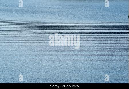 horizontal ripples across tranquil blue water surface Stock Photo