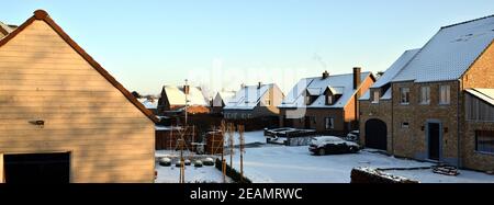 Typical Flemish suburb middle class detached houses with snow-covered roofs in a residential district. Stock Photo