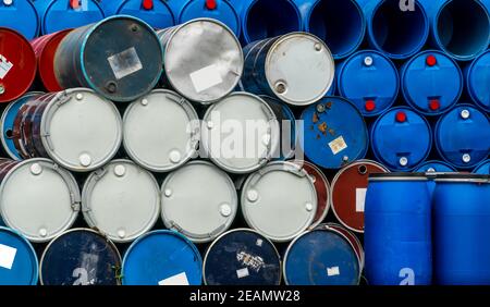 Old chemical barrels. Blue and red oil drum. Steel and plastic oil tank. Toxic waste warehouse. Hazard chemical barrel with warning label. Industrial waste in drum. Hazard waste storage in factory. Stock Photo