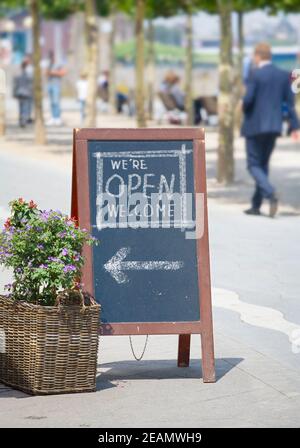 Welcome open sign, restaurant or cafe ready to service after corona lockdown,  food and drink concept,billboard, sandwich board in a cafe outside Stock Photo