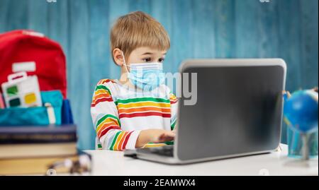Boy in medical face protection mask indoors on blue background Stock Photo