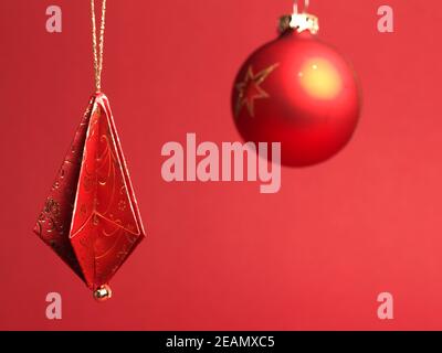 Christmas tree decorations folded from beautiful red and gold decorative paper against a red background Stock Photo