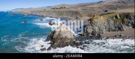 The Pacific Ocean washes against the shoreline of northern California on a beautiful day. The scenic Pacific Coast Highway runs this coastal area. Stock Photo