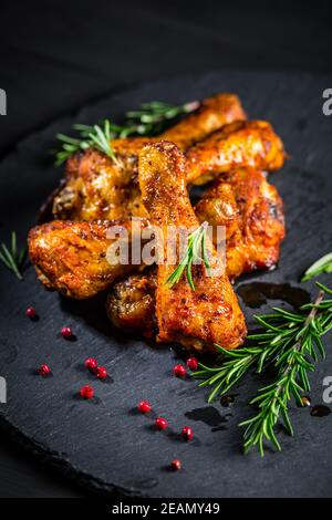 Hot spicy chicken legs with herbs on black background Stock Photo