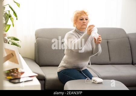 Elderly woman using asthma machine on light background Stock Photo