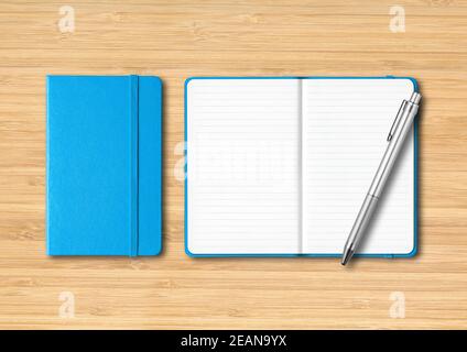 Blue closed and open lined notebooks with a pen on wooden background Stock Photo