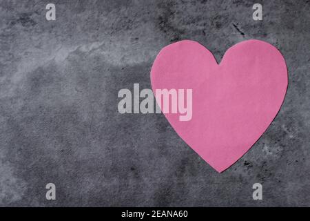 Pink paper heart shape on an abstract background in grey tones. Flat lay with empty space for text. Valentine's Day or love concept Stock Photo