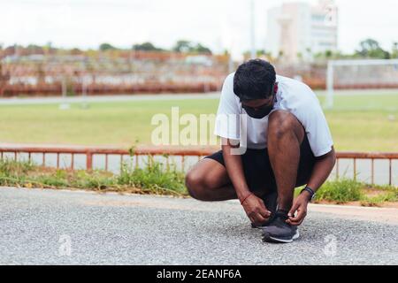 runner black man wear watch sitting he trying shoelace running shoes Stock Photo