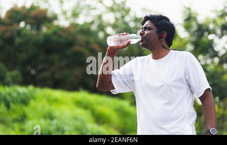 sport runner black man wear athlete headphones he drinking water from a bottle Stock Photo
