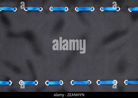 Blue satin ribbon inserted in the gold rings on black silk Stock Photo