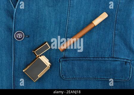 Cigar and lighter lying on a blue denim jacket Stock Photo