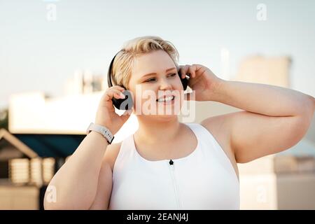 Plus size woman listening to music on the roof during training