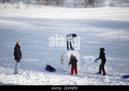 Edinburgh, UK. 10th Feb, 2021. Members of the public enjoying the the sunny day in Edinburgh. Storm Darcy hits Scotland in the South East of Edinburgh. The Inch. Pictured: Family building a huge snow ball. Credit: Pako Mera/Alamy Live News