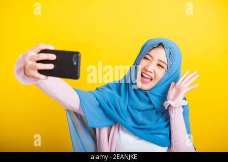 Asian Muslim Arab woman Islam wear hijab smile she taking making selfie with smart mobile phone Stock Photo