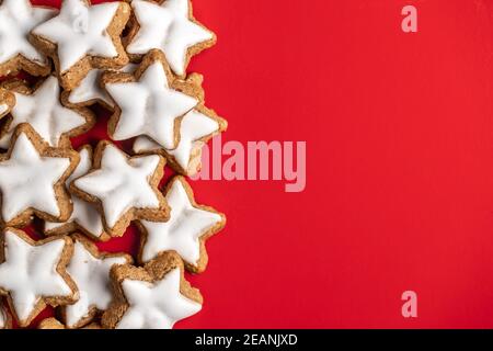 Icing gingerbread stars. Traditional Christmas cookies on red background. Stock Photo