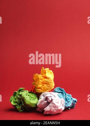 Colorful crumpled paper balls on a red studio background Stock Photo