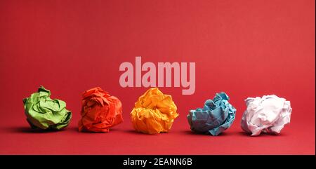 Colorful crumpled paper balls on a red studio background Stock Photo