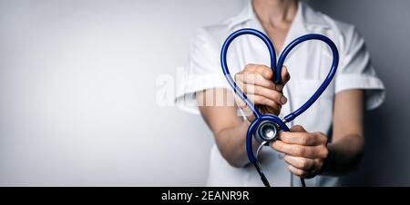 female doctor with heart shaped stethoscope. healthcare job love, cardiology or health insurance concept. copy space