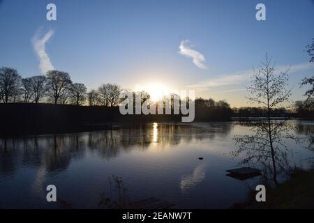 Winter sunrise across a lake surface highlighting the frozen ice patterns on the water. Stock Photo