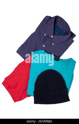 Closeup of a folded stylish violet shirt, a blue t-shirt, a black cap or hood and a red boxer short isolated on a white background. Mens fashionable outfit. Stock Photo