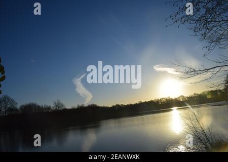 Winter sunrise across a lake surface highlighting the frozen ice patterns on the water. Stock Photo