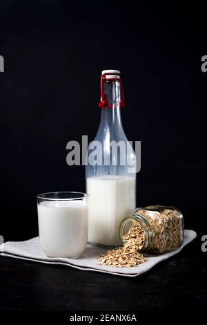 glass and bottle of vegetarian oatmeal milk on dark background. Stock Photo
