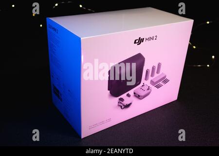 Kiev, Ukraine - February 02, 2021: Dji Mavic Mini 2 drone Bundle Fly More Combo white packaging box on black background in blue, purple, pink light Stock Photo