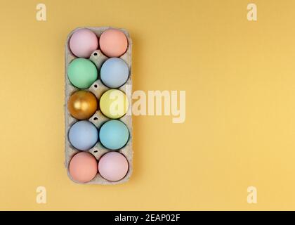 Multicolored wooden decorative Easter eggs in cardboard packaging on a yellow background. Happy Easter greeting card. Copy space. Stock Photo
