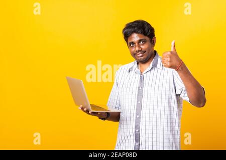 black man smiling standing wear shirt using laptop computer and showing thumb up Stock Photo