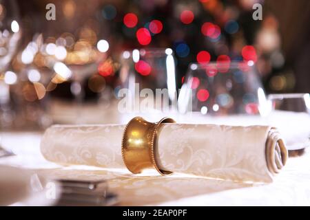 Beautiful Christmas table setting. The napkin is on the plate. Macro photo on the background of a Christmas tree. Stock Photo