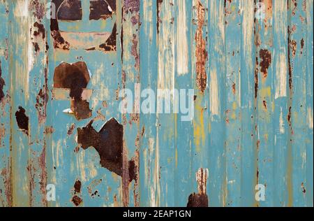 Old rusty metal painted with blue color. Empty blue wall texture background. Peeling paint on blue striped wall. Rust and oxidized metal. Closeup texture of old logistics container. Old iron panel. Stock Photo