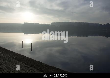Large reservoir reflects the sky at sunset during winter. Stock Photo
