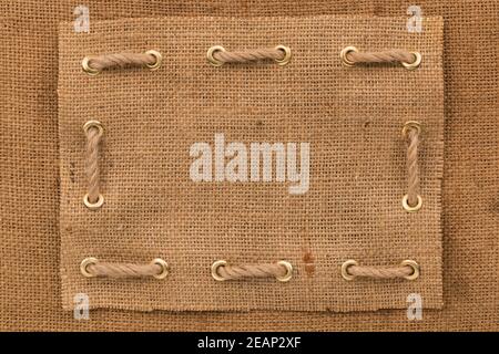 Frame burlap with one lines of rope inserted into gold rings. Top view. Stock Photo