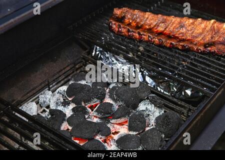 Close-up Of BBQ Roast and Smoked Pork Spareribs glazed with sauze On The Hot Charcoal Grill With Flames, Barbecue and hobby concept