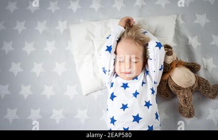 six years old child sleeping in bed with alarm clock Stock Photo