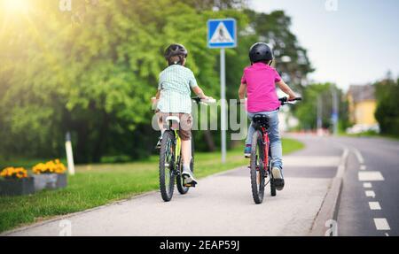 Children with rucksacks riding on bikes in the park near school Stock Photo